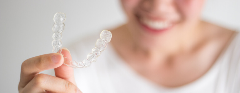 smiling woman holding ClearCorrect braces